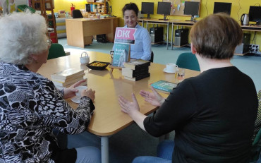 panie wraz z bibliotekarką dyskutują o książce siedząc przy stole