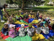 Bibliotekarka rozdaje dzieciom słodycze, a dzieci siedzą w kole na chuście