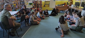 harcerze grają na gitarze, dzieci śpiewają na dywanie