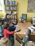 dzieci w asyście bibliotekarza wypożyczają swoją pierwszą książkę