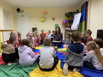 Dzieci siedzą na kolorowej chuście i odgadują zagadkę