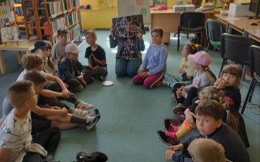 bibliotekarka pokazuje dzieciom książkę z dziurą