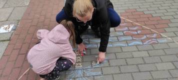Rysowanie kredą na chodniku przez uczestników spotkania