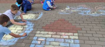 Rysowanie kredą na chodniku przez uczestników spotkania