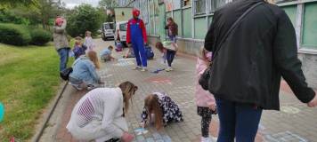 Rysowanie kredą na chodniku przez uczestników spotkania