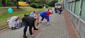 Rysowanie kredą na chodniku przez uczestników spotkania