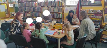 dzieci z mamami wykonują przy stole pracę plastyczną