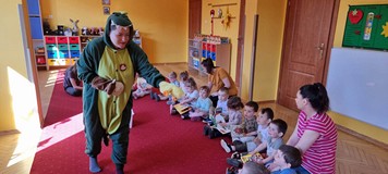 bibliotekarka w stroju smoka pokazuje dzieciom pacynkę