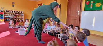 bibliotekarka w stroju smoka pokazuje dzieciom pacynkę