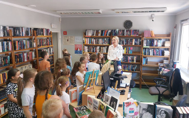 Bibliotekarka oprowadza grupę uczniów po bibliotece