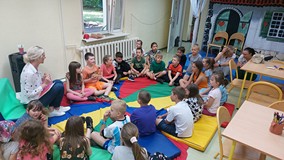 Dzieci wraz z bibliotekarką siedzą na chuście animacyjnej podczas zajęć