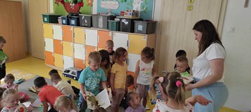 bibliotekarka rozdaje dzieciom książki, które przywiozła z biblioteki