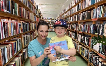 Dziecko i bibliotekarka prezentują książkę