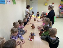 Dzieci przystolikach czekają na kolorowankę