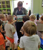Pani Ania pokazuje dzieciom książkę o dinozaurach