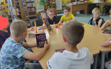 dzieci siedzą przy stole i dyskutują o przeczytanej książce