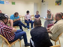 Uczestnicy siedzą na krzesłach w kole wraz z bibliotekarką