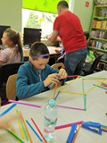 Uczestnicy budują stabilną konstrukcję z kolorowych słomek