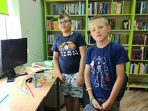 Dwaj chłopcy demonstrują zbudowaną przez siebie, wytrzymałą konstrukcję ze słomek