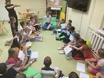 Dzieci podczas zajęć siedzą na materacykach i rozmawiają o książkach