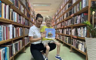 Chłopiec i bibliotekarka prezentują książeczkę