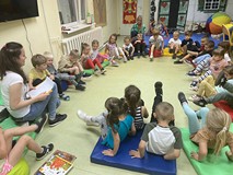 Dzieci podczas zajęć siedzą na materacykach i rozmawiają o jesieni