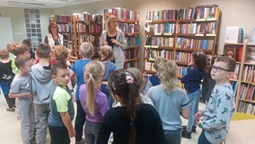 Bibliotekarka oprowadza uczniów po bibliotece