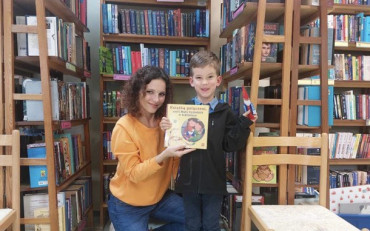 Chłopiec i bibliotekarka prezentują książeczkę
