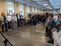 Uczestnicy wernisażu na tle wystawy.