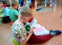 Na zdjęciu przedszkolaki siedzą na podłodze i przeglądają najpiękniejsze książeczki dla dzieci z nas