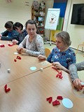 Uczestnicy siedzą przy stolikach i tworzą kotyliony