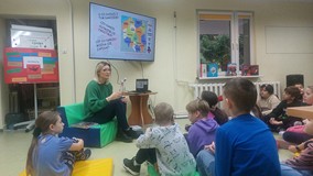 Uczniowie seidzą naprzeciwko bibliotekarki słuchając lekcji o odzyskaniu niepodległości przez polakó
