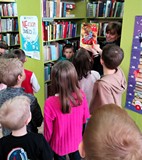 Bibliotekarka pokazuje dzieciom lekturę „Plastusiowy pamiętnik”