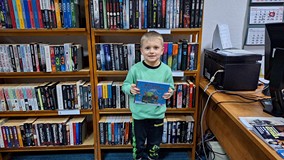 chłopiec pozuje do zdjęcia z pakietem 