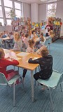 bibliotekarka tłumaczy dzieciom technikę malowania pędzlem