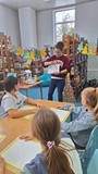 bibliotekarka tłumaczy dzieciom technikę malowania pędzlem