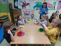 Dzieci siedzą przy stolikach i wykonują doświadczenie