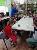 Dzieci czekają na reakcję chemiczną - zmianę koloru płynu w kubeczkach
