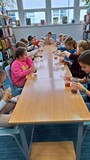 dzieci siedzą przy stołach i wykonują eksperymenty