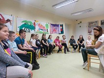 Prowadząca opowiada dzieciom o wężu, którego trzyma na kolanach