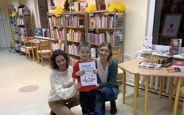 Chłopiec pozuje z dyplomem i bibliotekarkami