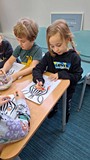 dzieci wykonują pracę plastyczną przy stołach