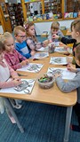 dzieci wykonują pracę plastyczną przy stołach