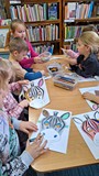 dzieci wykonują pracę plastyczną przy stołach