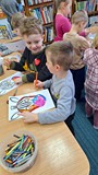 dzieci wykonują pracę plastyczną przy stołach