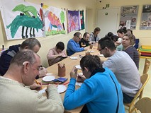 Uczestnicy spotkania siedzśą przy stołach i rysują