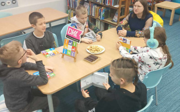 dzieci siedzą przy stole z bibliotekarką i dyskutują o przeczytanej książce