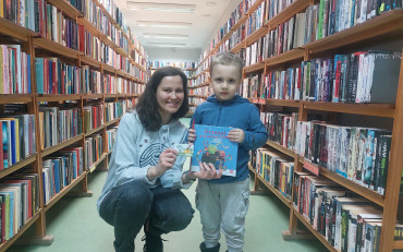 Bibliotekarka i chłopiec prezentują książeczkę