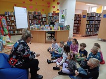 Na zdjęciu przedszkolaki siedzą na podłodze, a Gosia prezentuje książeczki o Śwince Malince i Słoniu