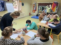 Uczestnicy siedzą przy stolach i rysują
